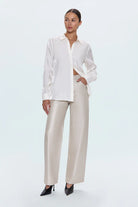 Woman wearing a white blouse and beige pants on a white background