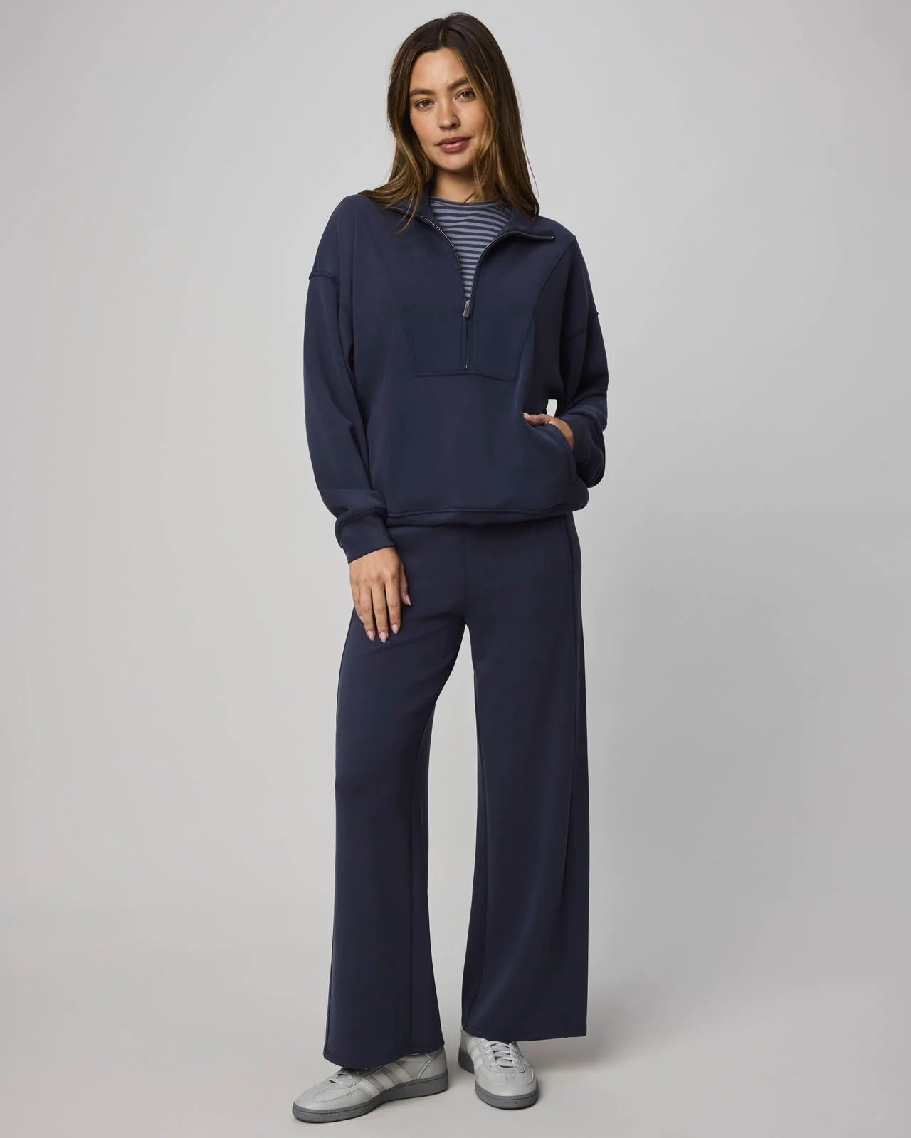 Woman wearing a navy blue outfit with wide-leg pants on a gray background