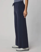 Navy blue pants worn by a person on a gray background