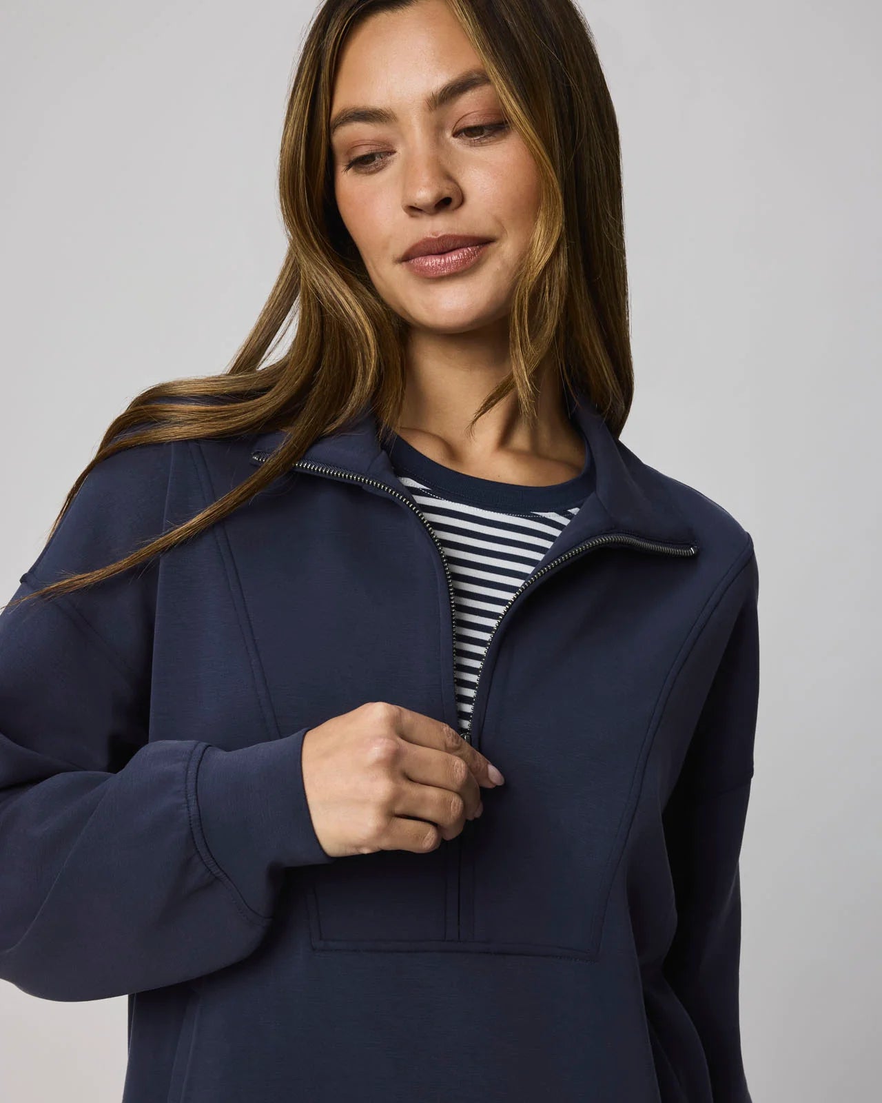 Woman wearing a navy blue jacket over a striped shirt on a plain background