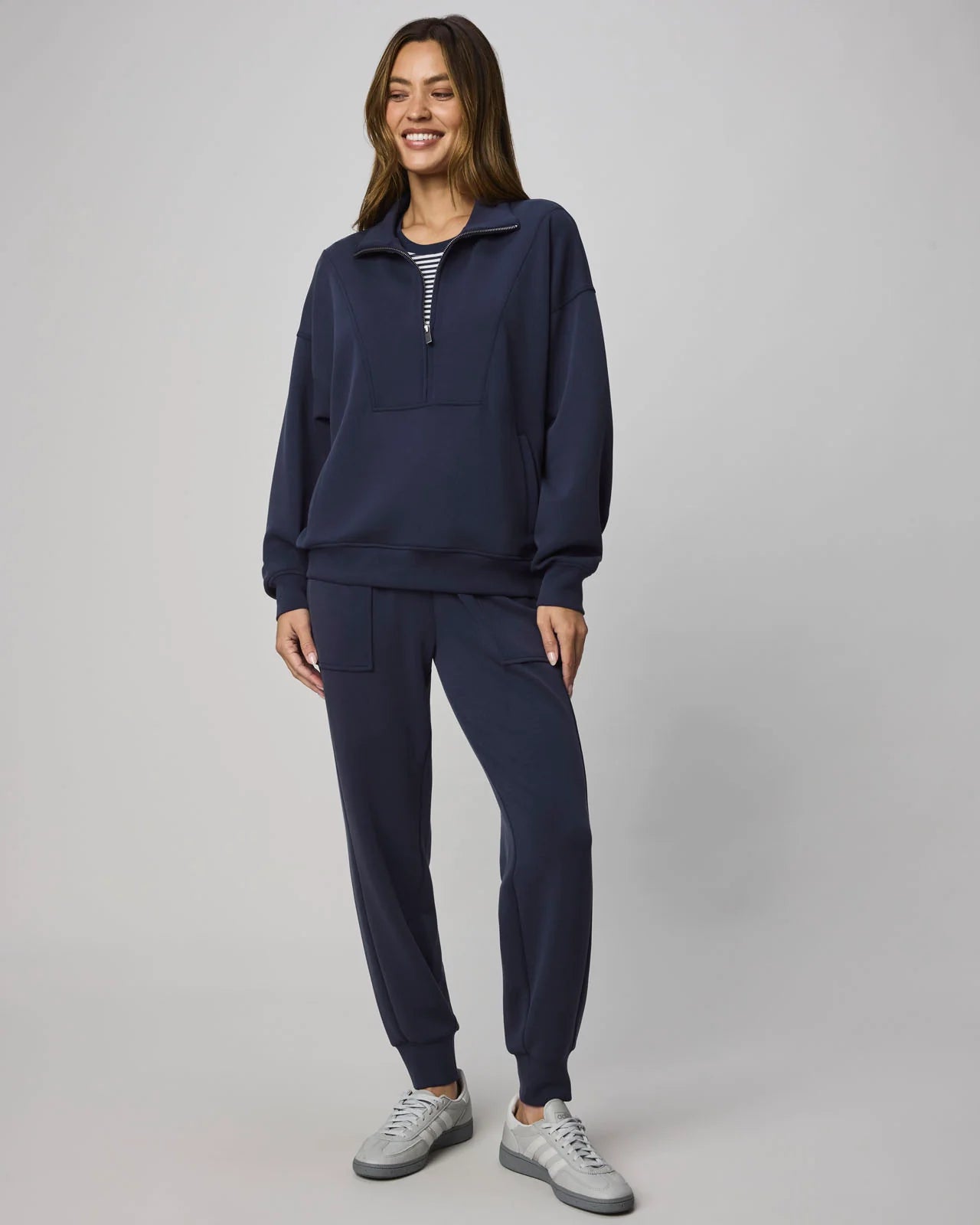 Woman wearing a navy tracksuit with a white background
