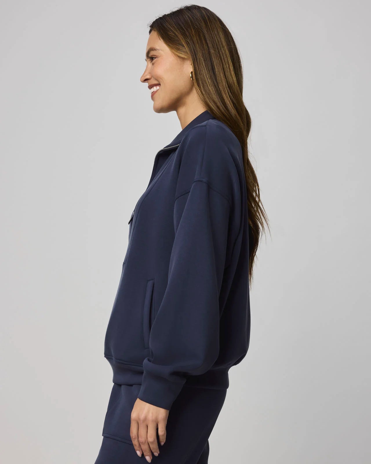 Woman wearing a navy blue tracksuit against a light gray background