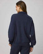 Person wearing a navy blue tracksuit against a gray background