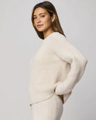 Woman wearing a cream sweater against a plain background