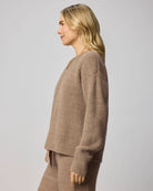Woman wearing a brown ribbed sweater against a plain background
