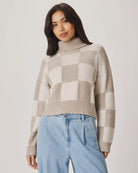 Woman wearing a checkered sweater and blue jeans against a plain background