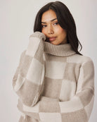 Woman wearing a checkered sweater against a plain background