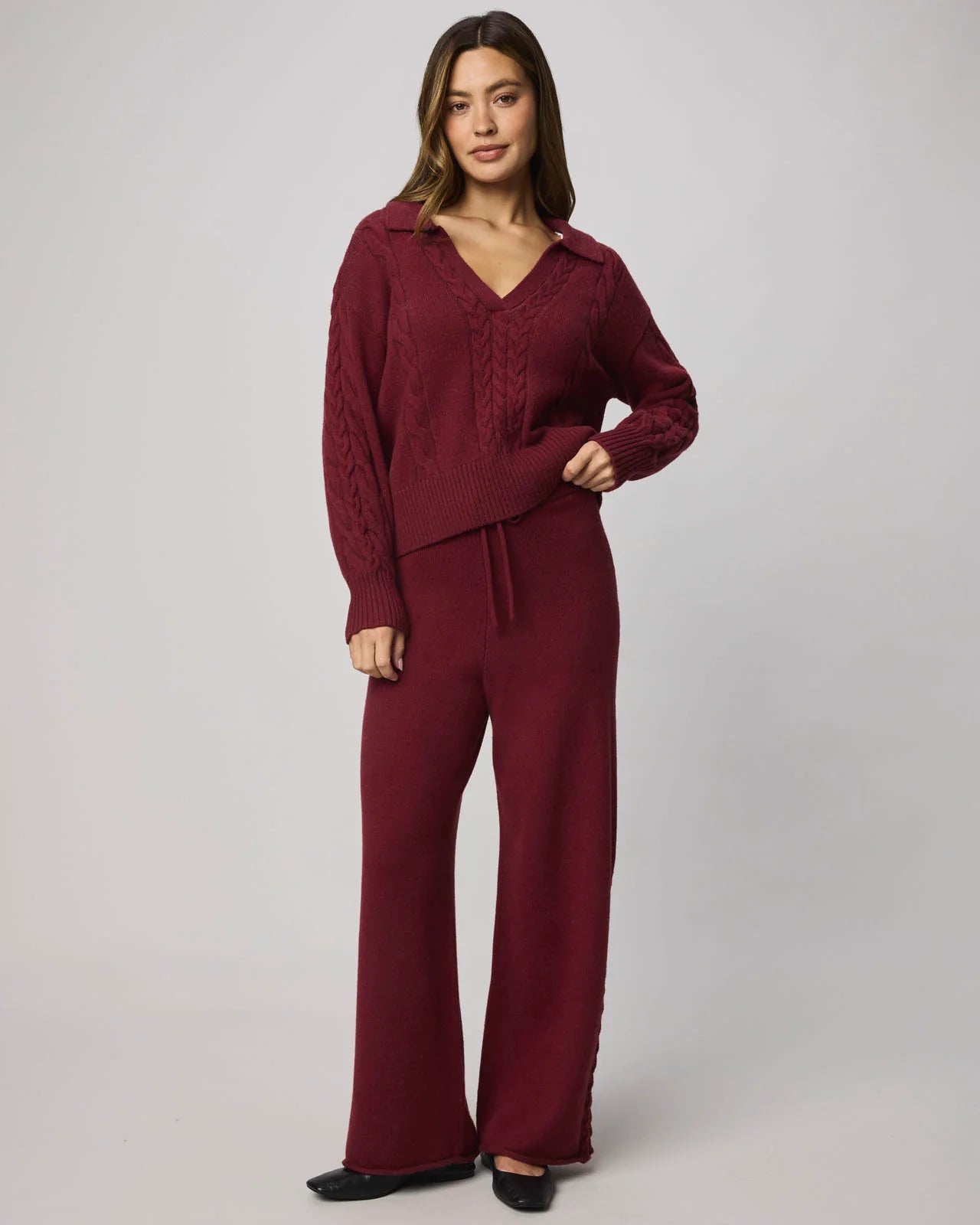 Woman wearing a burgundy outfit with a matching top and pants on a plain background