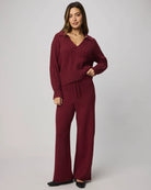 Woman wearing a burgundy outfit with a matching top and pants on a plain background
