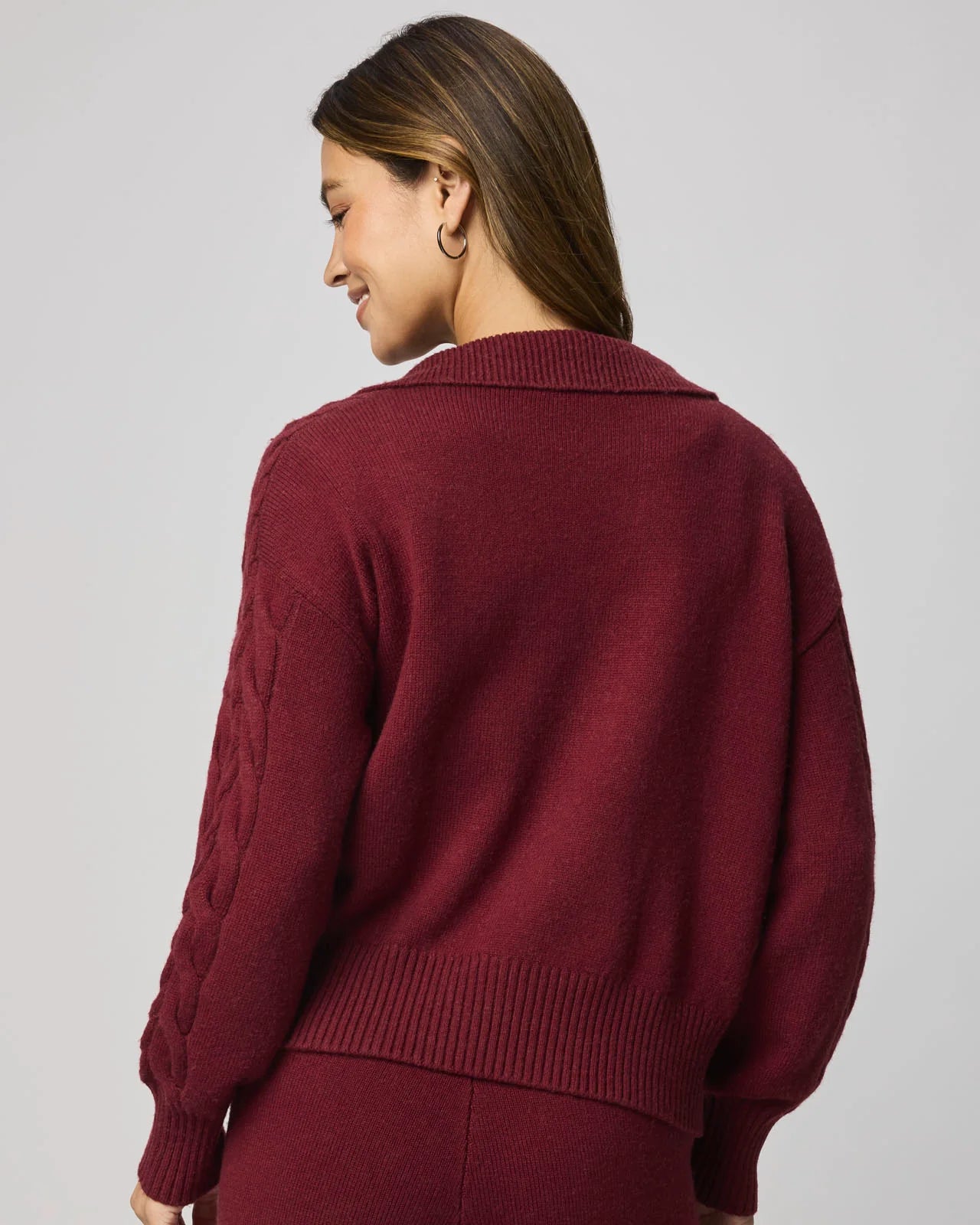 Person wearing a burgundy sweater against a plain background