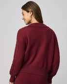 Person wearing a burgundy sweater against a plain background