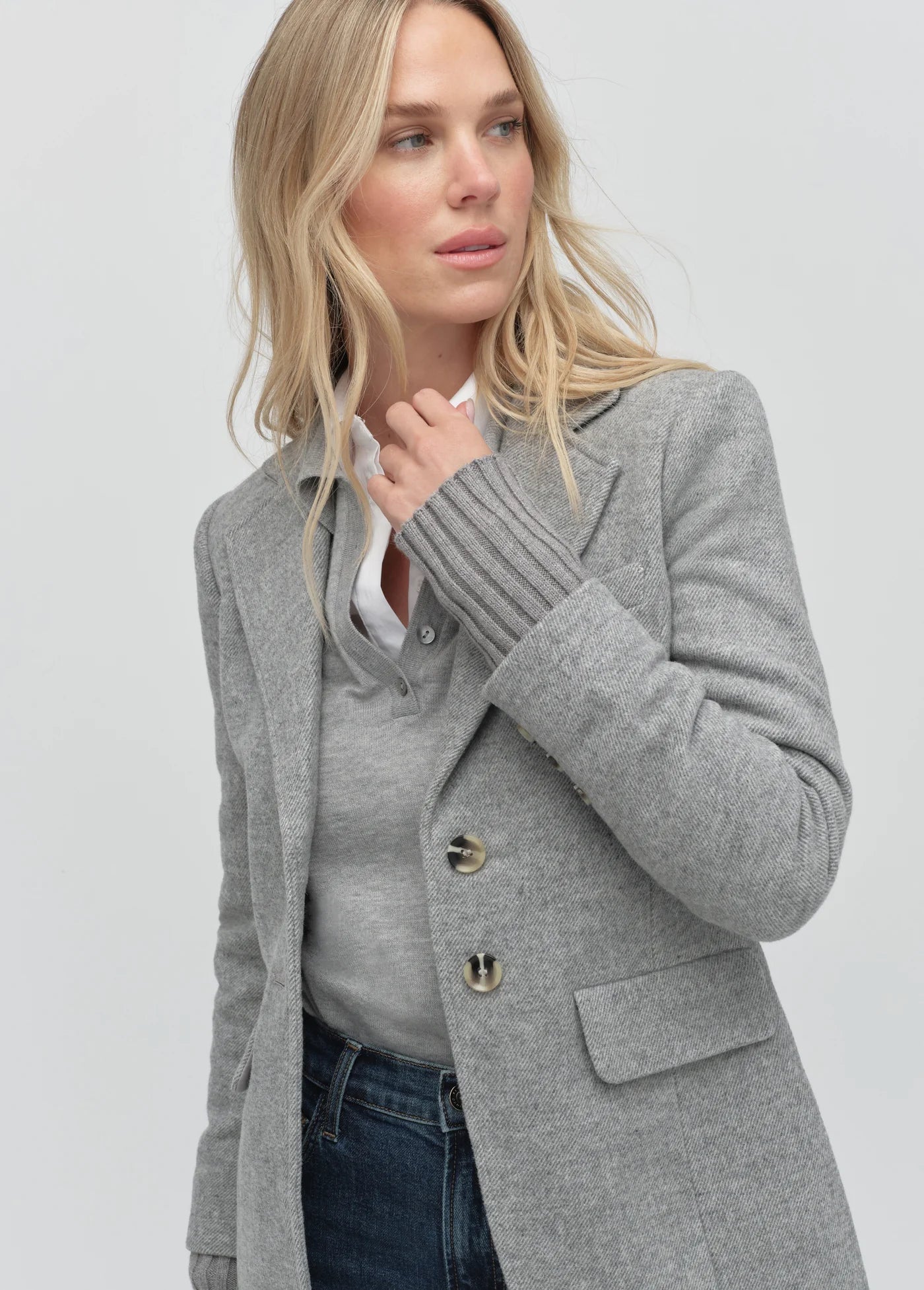 Woman wearing a gray coat on a plain background