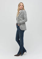 Woman wearing a gray blazer and blue jeans on a white background