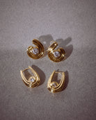 Gold hoop earrings with gemstones on a gray background